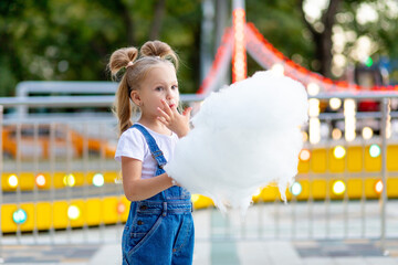 happy girl at an amusement park eating cotton candy in the summer