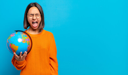 young hispanic woman shouting aggressively, looking very angry, frustrated, outraged or annoyed,...