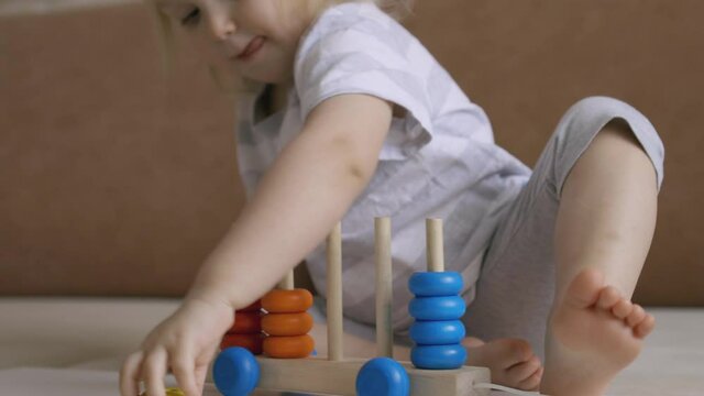 Little girl playing wooden education games on the table. Sorting rainbow wheels. Handheld Close Up Shot.