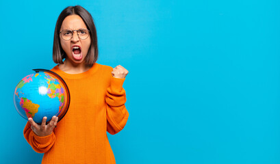 young hispanic woman shouting aggressively with an angry expression or with fists clenched...