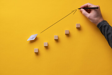 Drawing an arrow pointing upwards in front of an origami made paper boat