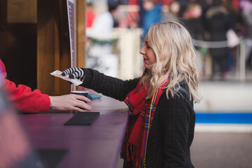 A young blonde woman purchases a hot drink from a vendor to keep warm while attending the Edinburgh...