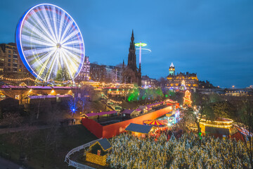 A vibrant and lively view of the Edinburgh Christmas Market at Princes Street Gardens in Scotland at night all lit up and illuminated with Christmas lights. - obrazy, fototapety, plakaty
