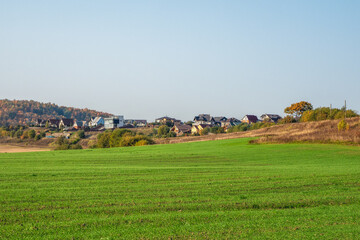 Obraz premium Modern cottage village in a green field. The village in the green hollow.