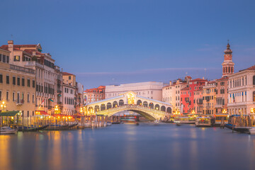 A long exposure of the Grand Canal and Rialto Bridge in Venice, Italy during evening blue hour.