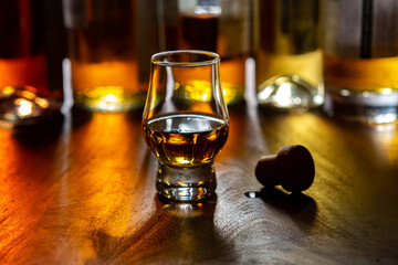 Dram of single malt scotch whisky and bottles on background
