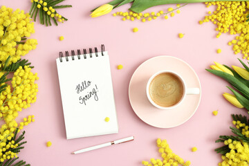 Hello Spring text on notebook, cup of coffee, yellow mimosa branches and tulips on pastel pink background. Spring, springtime, march, equinox concept. Top view. - obrazy, fototapety, plakaty