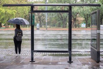 Woman waiting on a bus stop in a rainy day in Buenos Aires - Argentina.