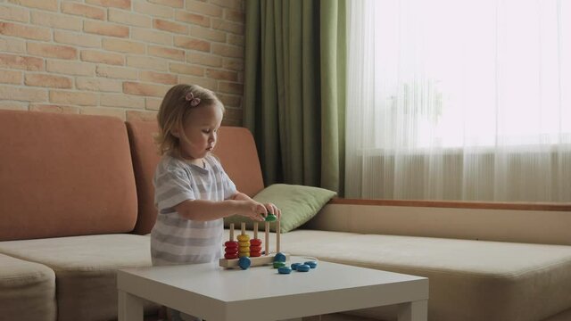 Little girl playing wooden education games on the table. Sorting rainbow wheels. Medium shot.
