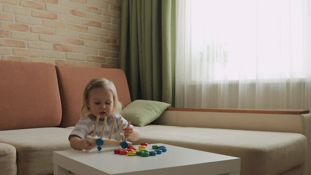 Little girl playing wooden education games on the table. Sorting rainbow wheels. Medium shot.