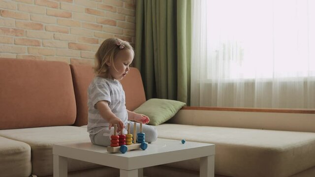 Little girl playing wooden education games on the table. Sorting rainbow wheels. Medium shot.