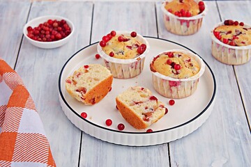 Lingonberry muffins in white paper forms on a white ceramic plate. Muffin recipes.