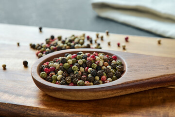 Variety of colored peppercorns on a wooden spoon, spice, macro