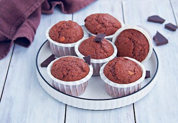Chocolate muffins in white paper forms on a white ceramic plate