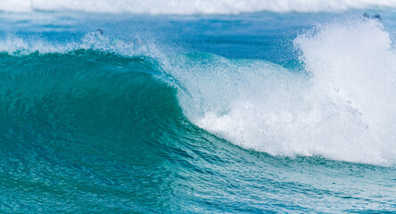Vague qui déroule sur un spot de surf en Guadeloupe avec une mer variant du vert émeraude au bleu...