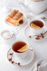 Two cup of tea with a slice of lemon in porcelain teapot on light background. English teatime