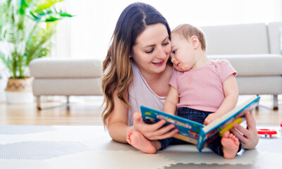 a happy mother with baby reading book. Baby is thinking