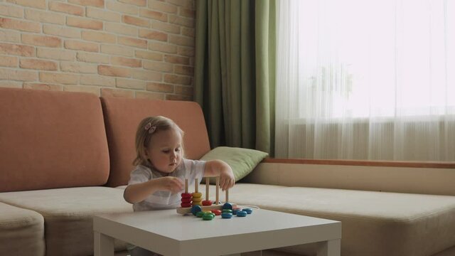 Little girl playing wooden education games on the table. Sorting rainbow wheels. Medium shot.