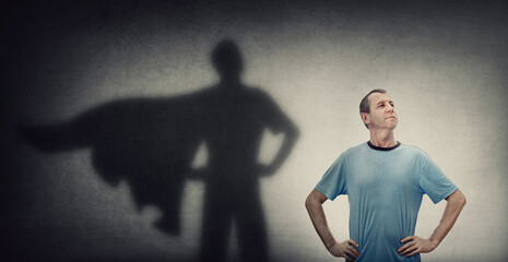Confident and optimistic middle aged man, hands on hips showing chest, brave gesture, like a powerful superhero casting shadow on the wall. Inner strength, motivation and ambitions, leadership concept © 1STunningART