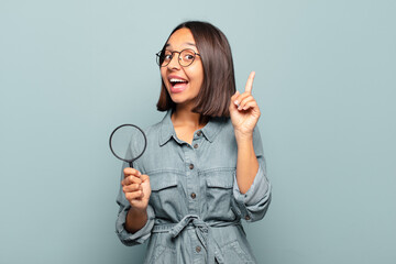 young hispanic woman feeling like a happy and excited genius after realizing an idea, cheerfully...