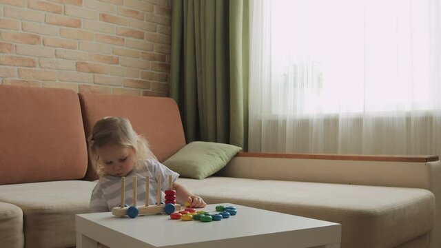 Little girl playing wooden education games on the table. Sorting rainbow wheels. Medium shot.