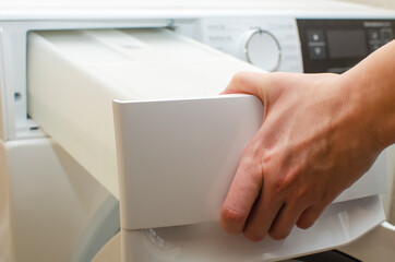 A container for condensate from the dryer, a woman takes out a tank with accumulated water after...