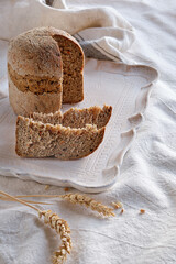 Dinkelbrot in German that means spelt wholemeal bread. The wheat alternative. Dinkel or Spelt is an ancient grain grown organically in Europe. Off white textile background with wheat ears.