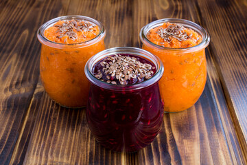 Closeup on vegetable smoothies or puree with flax seeds in the glass jars on the wooden table