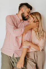 Fototapeta premium Romantic couple in bright summer clothes with smile posing on white background. Guy and girl hug and enjoy good mood