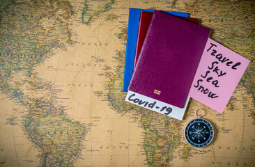 Passports with note COVID-19  and compass,on the world map background. Coronavirus outbreak situation, traveling after pandemic