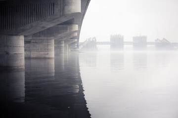 Contrasty image of two bridges over a river with one is already built and another one still in...