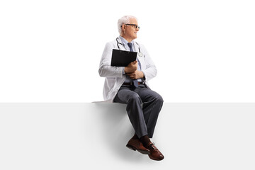 Full length shot of a mature doctor sitting on a blank panel and looking to the side