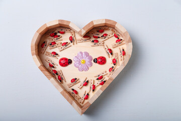 Heart shaped box with small wooden decorative pins with tiny red ladybugs for handwork, handmade decorations, leisure time. Spring and love, first date, Valentines day concept. Copy space.