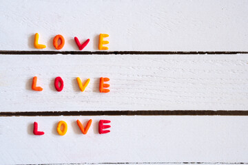 Word love colorfull, hand made on white wooden background. Minimal love concept. Flat lay.