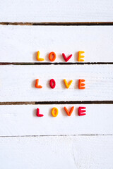 Word love colorfull, hand made on white wooden background. Minimal love concept. Flat lay.