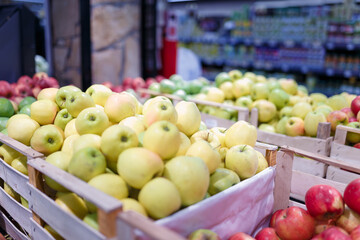 Soft focused shot of fruit department in grocery store, supermarket, mall, hypermarket or shopping center. Boxes of multicolored apples. Healthy eating, avitaminosis, diet, organic, vegan food.