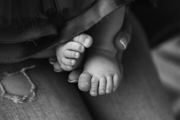 Tiny baby feet of the firstborn in the loving arms of a young mother