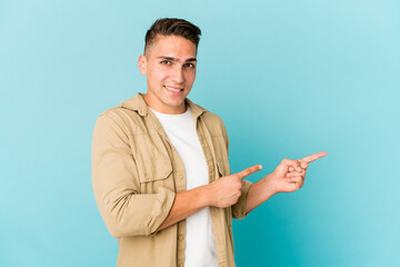 Young caucasian handsome man isolated shocked pointing with index fingers to a copy space.