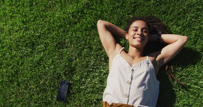 Portrait of african american woman lying on grass looking at camera smiling