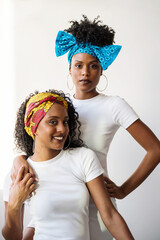 Portrait of two beautiful black women wearing traditional colorful african hair scarfs