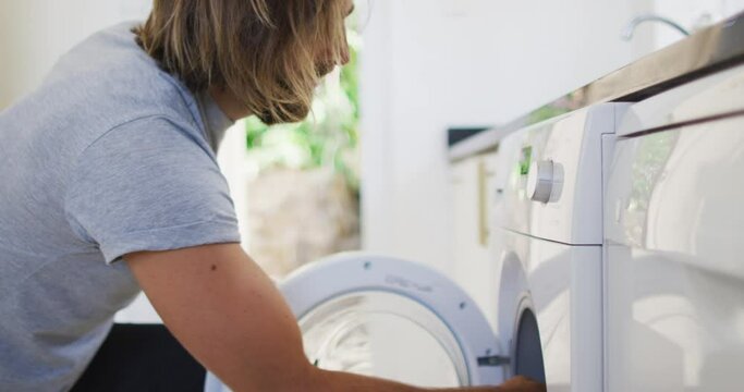 Caucasian man putting apron in the washing machine at home