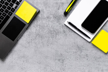 Laptop, phone, and office supplies on a gray concrete table. Workplace. A study table. Remote work. Distance learning. uminous yellow and extremely gray. The color of 2021. Copy space