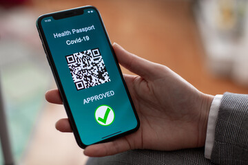 Vaccinated person using digital health passport app in mobile phone for travel during covid-19 pandemic.