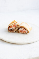 Wrapped crepes with smoked salmon and cream cheese on neutral background