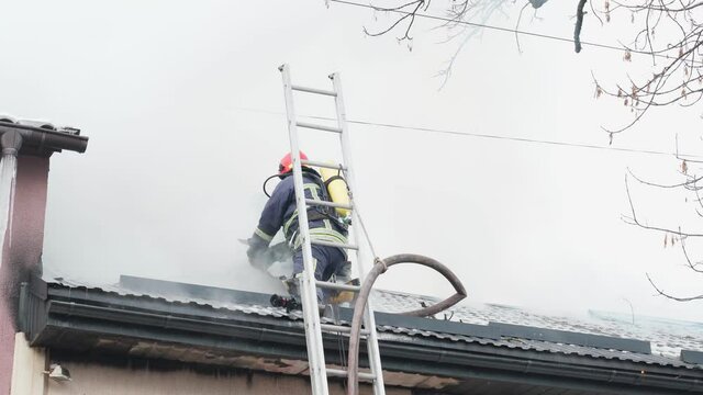Fireman working on roof and extinguish flame.