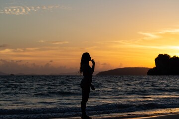 Fototapeta premium Woman posing at sunset on a beach in a swimsuit 