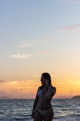 Woman posing at sunset on a beach in a swimsuit
