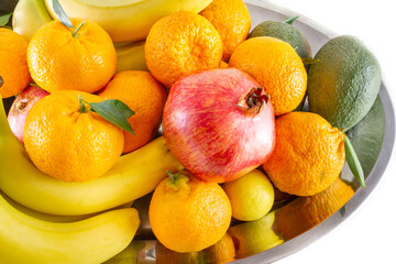 Assorted fruit and vegetable platter of bananas, pomegranate, lemon, tangerine and avocado.