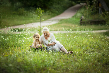 Old woman bath little girl in a basin outdoor in summer day around flowers