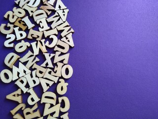 wooden letters of the alphabet scattered on a purple background with space for text. High quality...